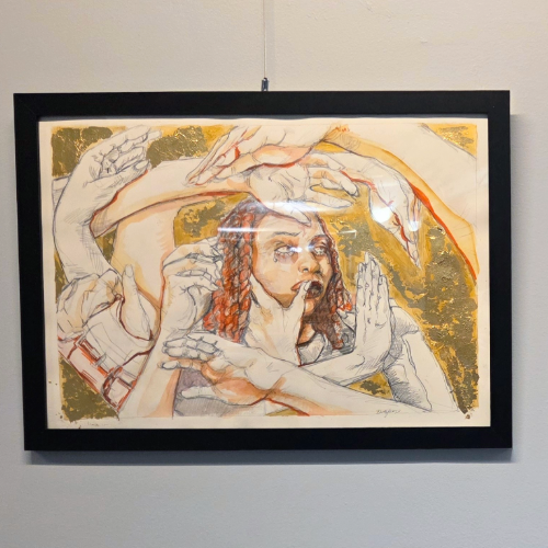 an image of a piece of asrtwork with a womans face surrounded by many hands wrapping around her, she has red curly hair and tears falling from her eyes. The image is framed in a black picture frame and hung from a silver wire.