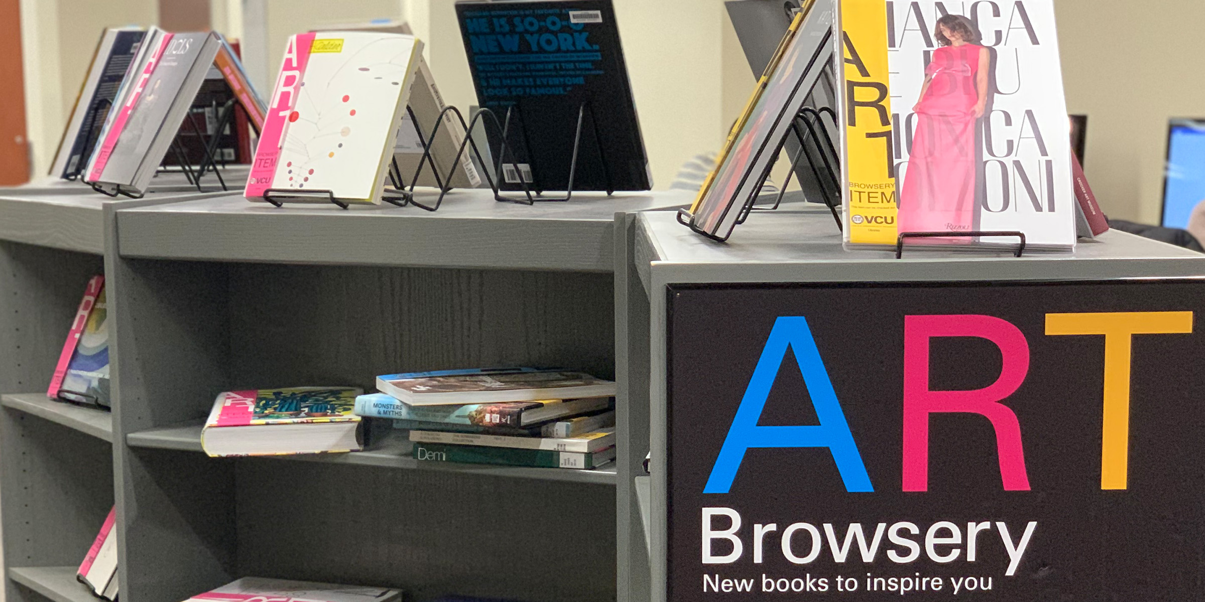 A bookcase with art books displayed and a sign which reads