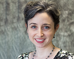 Portrait of Antonia Vassar in front of a grey speckled backdrop. Pronouns She/Her.
